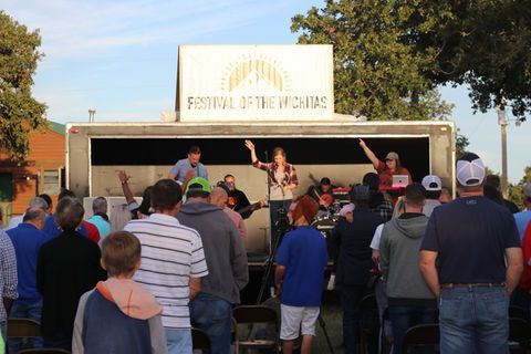A group of people are standing in front of a stage at a festival.