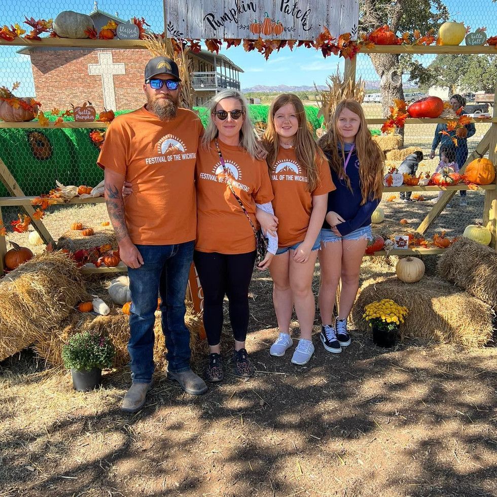 A family is posing for a picture at a pumpkin patch.