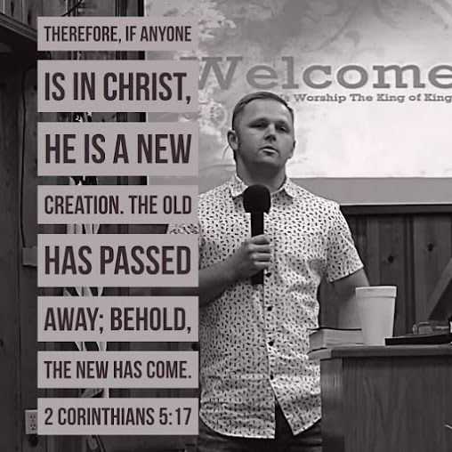 A man is holding a microphone in front of a sign that says welcome.