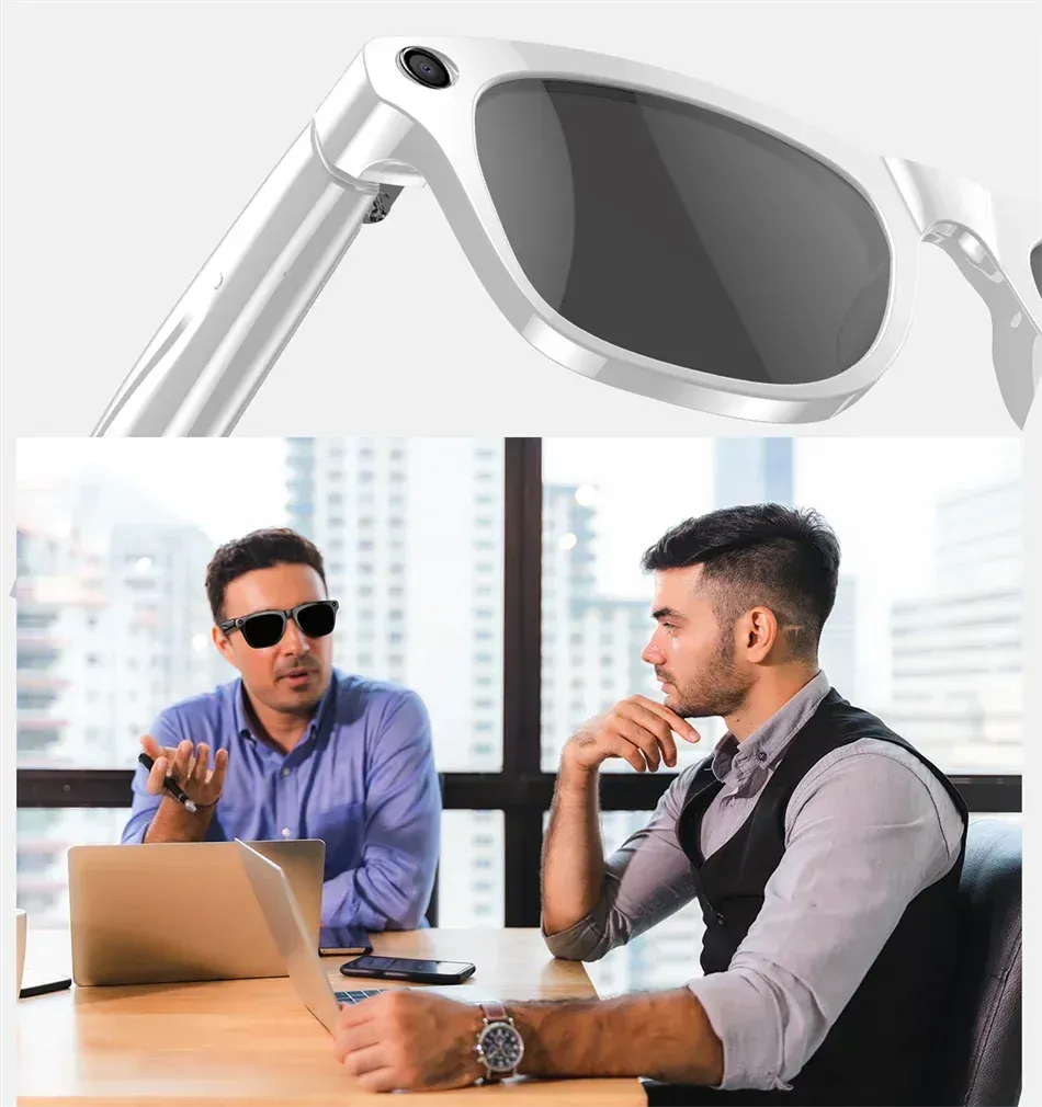 Two men wearing sunglasses are sitting at a table with a laptop.