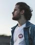 A man wearing a white vans shirt and a denim jacket