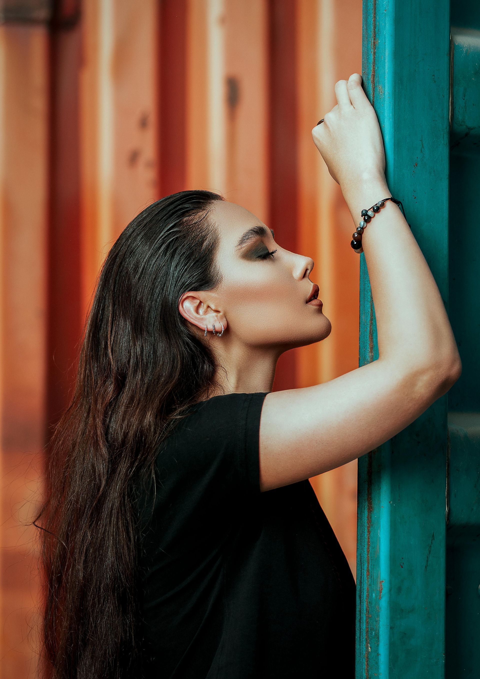 A woman with long hair is leaning against a blue wall.