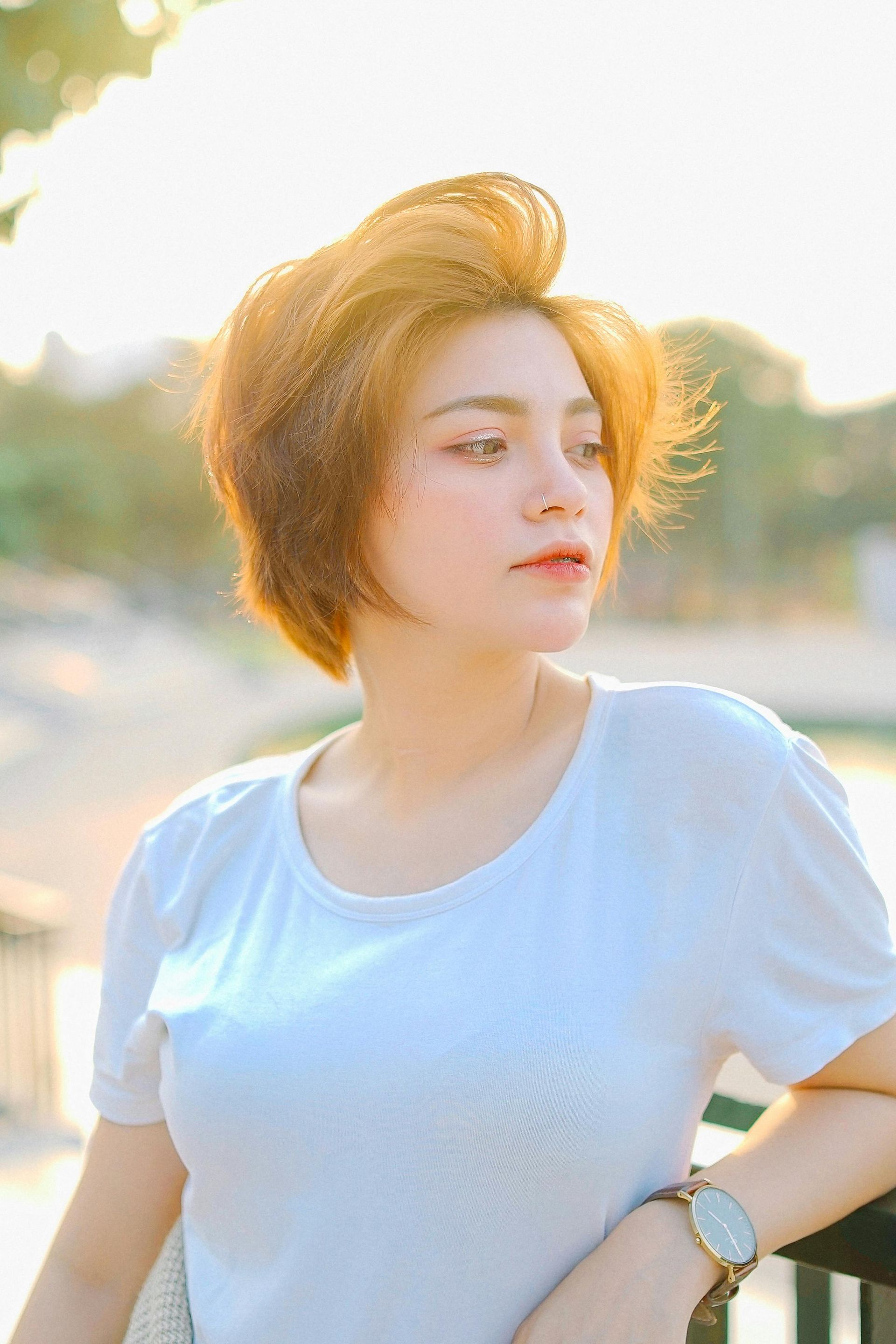 A woman with short hair is wearing a white shirt and a watch.