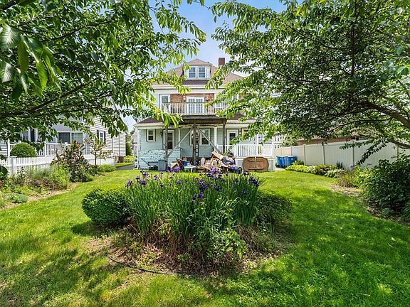 A large gray house is surrounded by trees and a driveway.