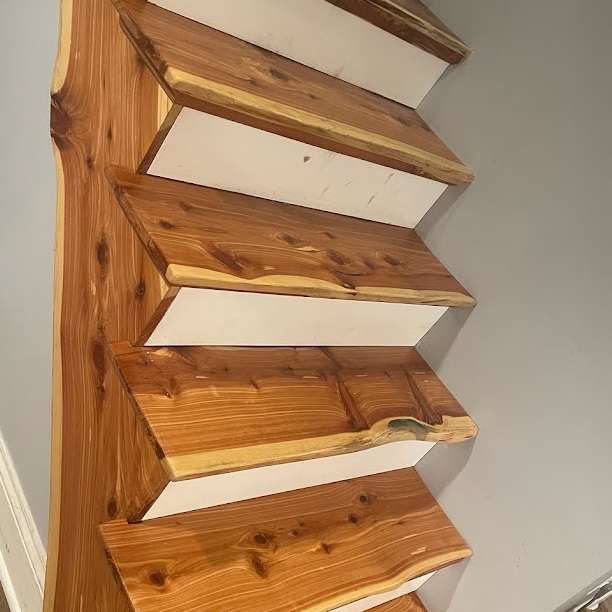 Wooden staircase with natural edge steps, cedar treads, and white risers against a gray wall.