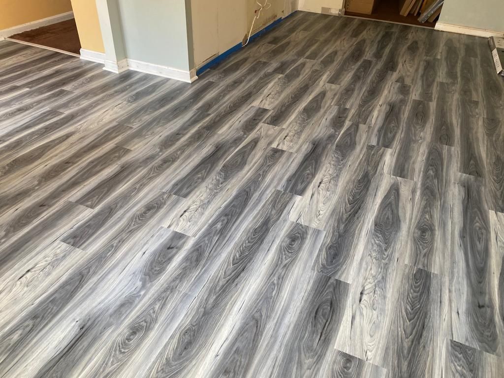Gray and white wood-look flooring installed in a room, with visible wood grain and varying plank lengths.