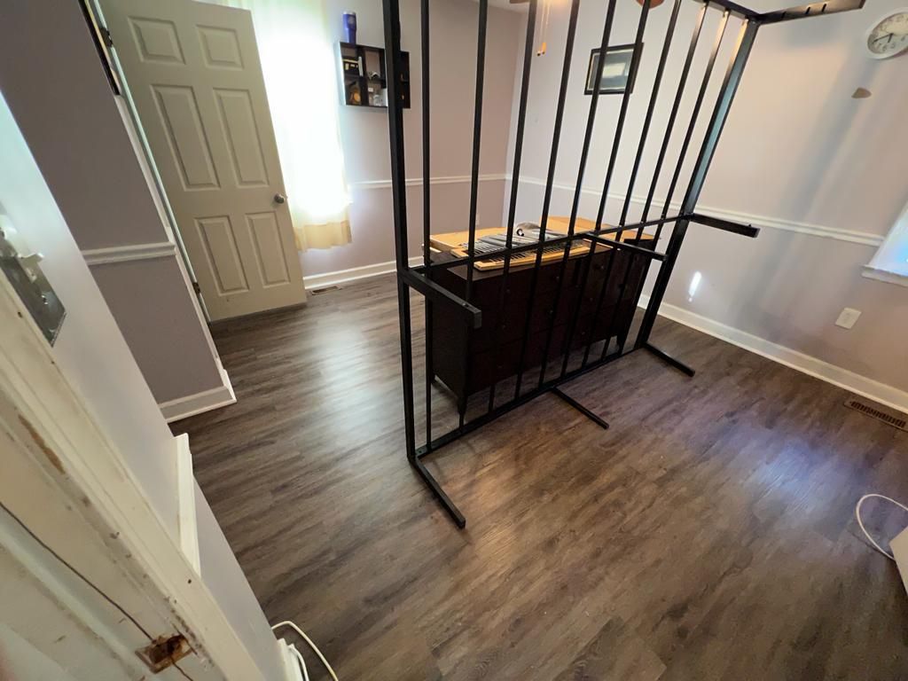 Black metal bed frame in a room with wood-look flooring, a door, and a window.