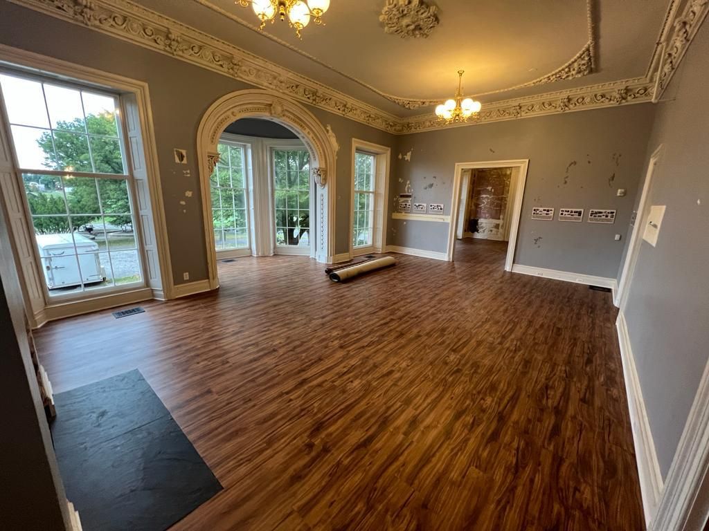 Elegant room with wood floors, large windows, and decorative ceiling molding.