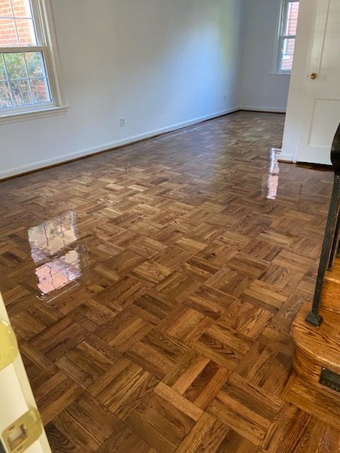 Wooden parquet flooring in a room with white walls, natural light.