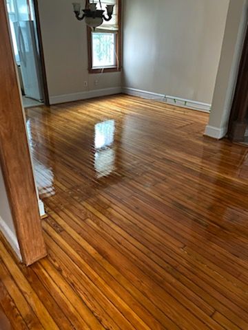 Wooden floor reflecting light in an empty room, with cream walls and a chandelier.
