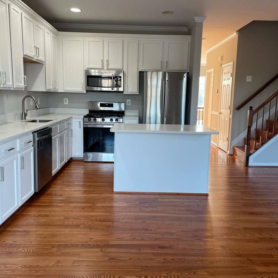 Bright kitchen with white cabinets, stainless steel appliances, and hardwood floors.