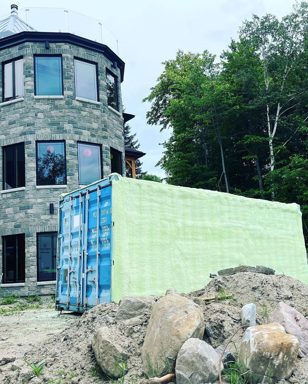 A large brick building with a blue shipping container in front of it.