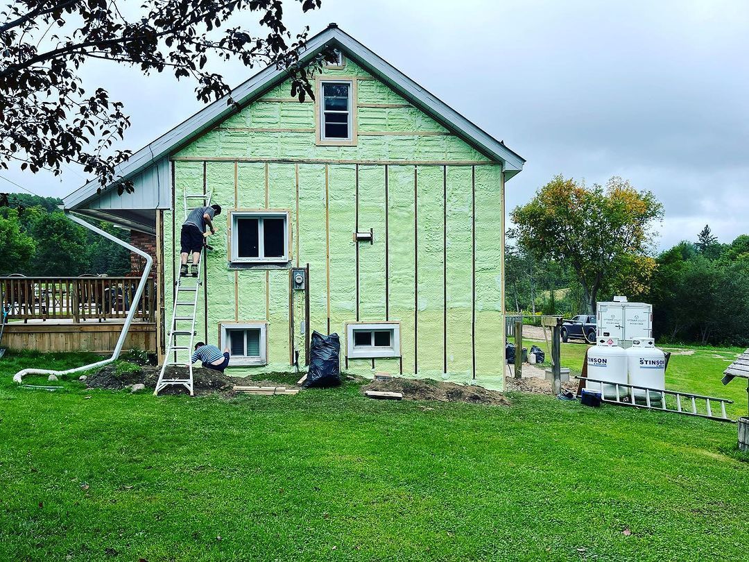 A green house is being insulated in a grassy field.
