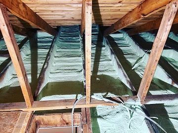 A picture of the inside of an attic with wooden beams and insulation.