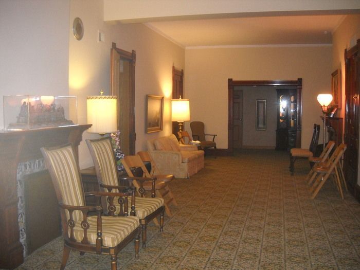Hallway with chairs and lamps; a neutral color scheme in a possibly historic building.