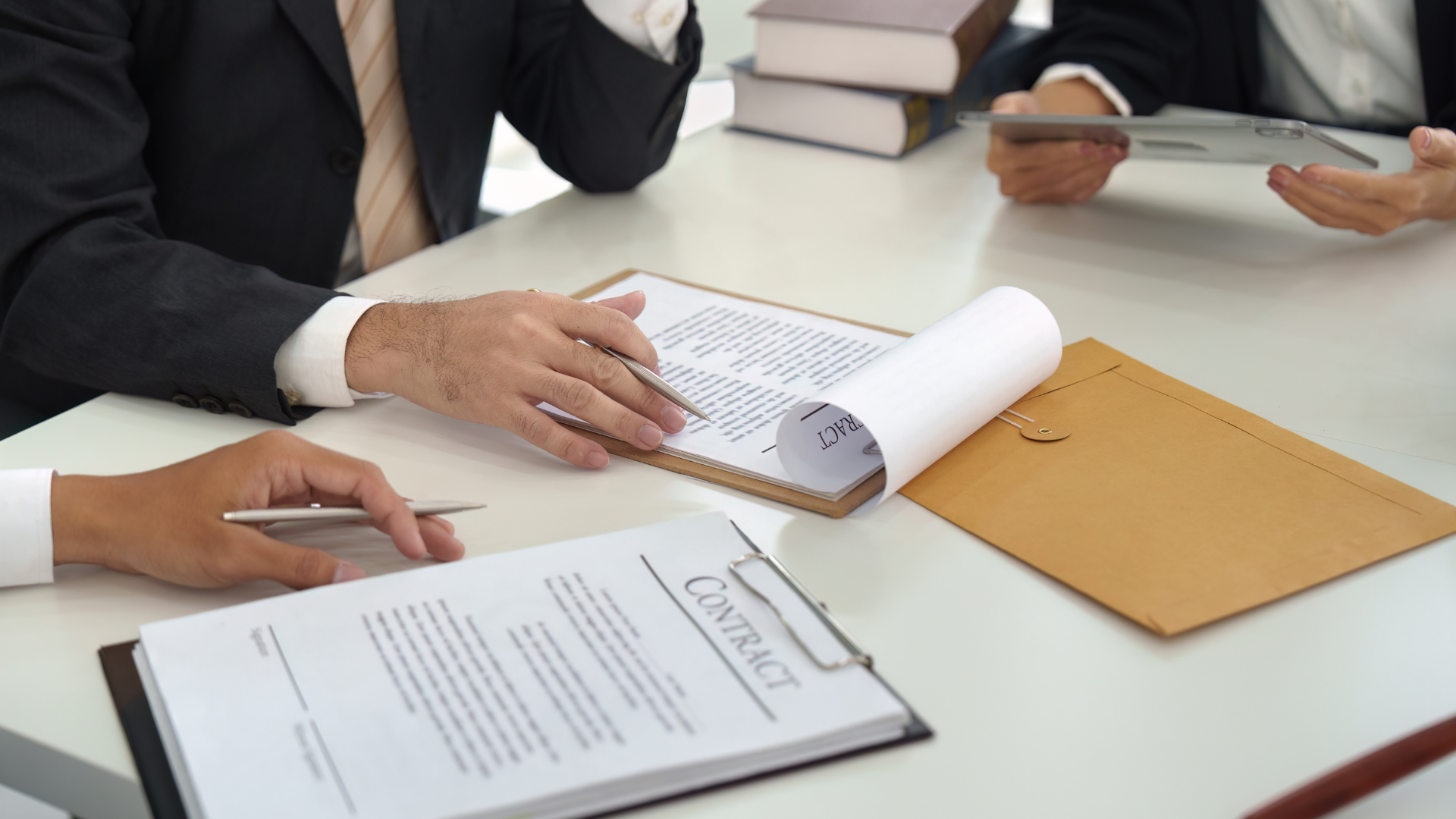 People in suits reviewing and signing contracts at a table.