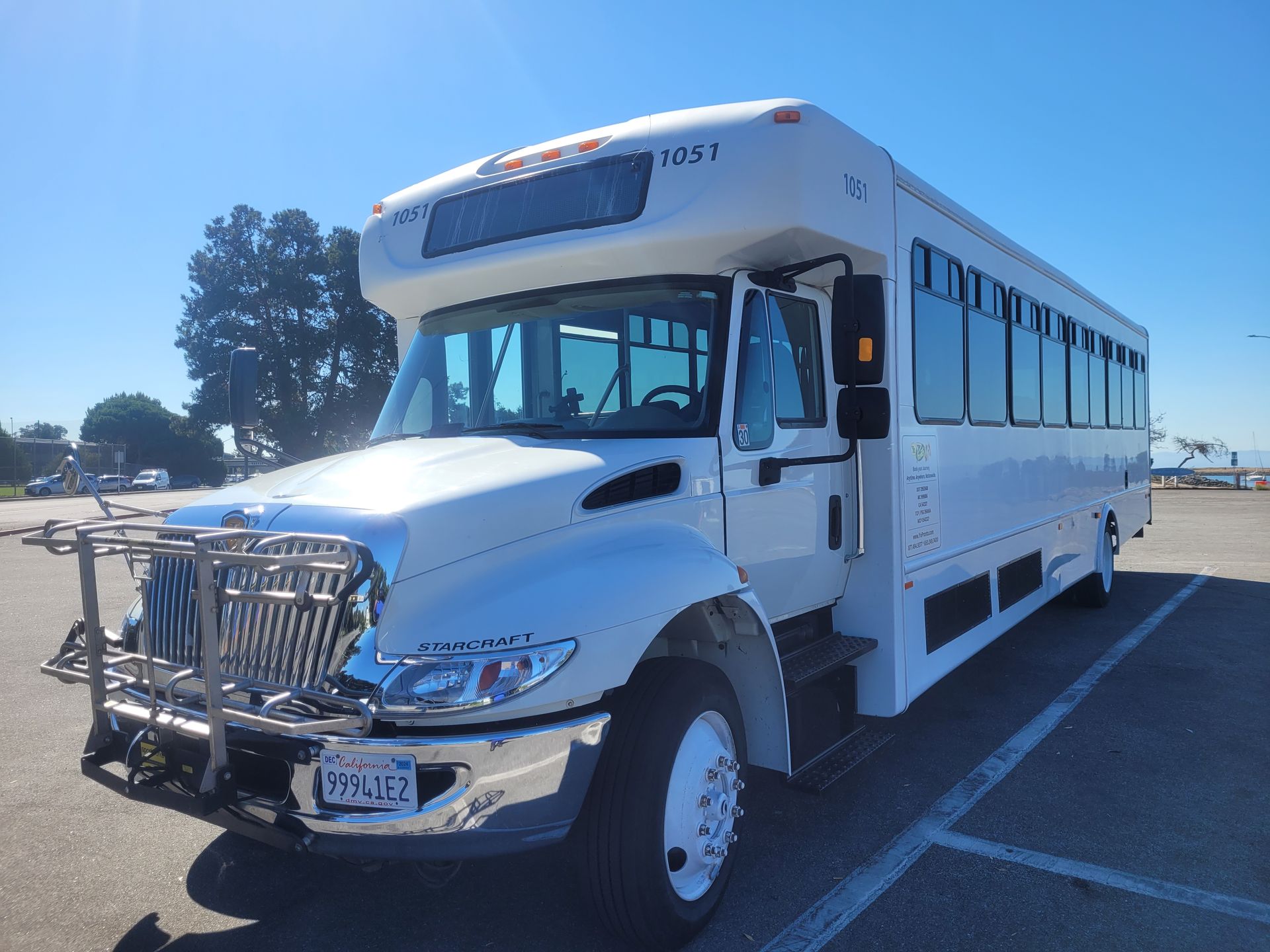 A large white bus is parked in a parking lot