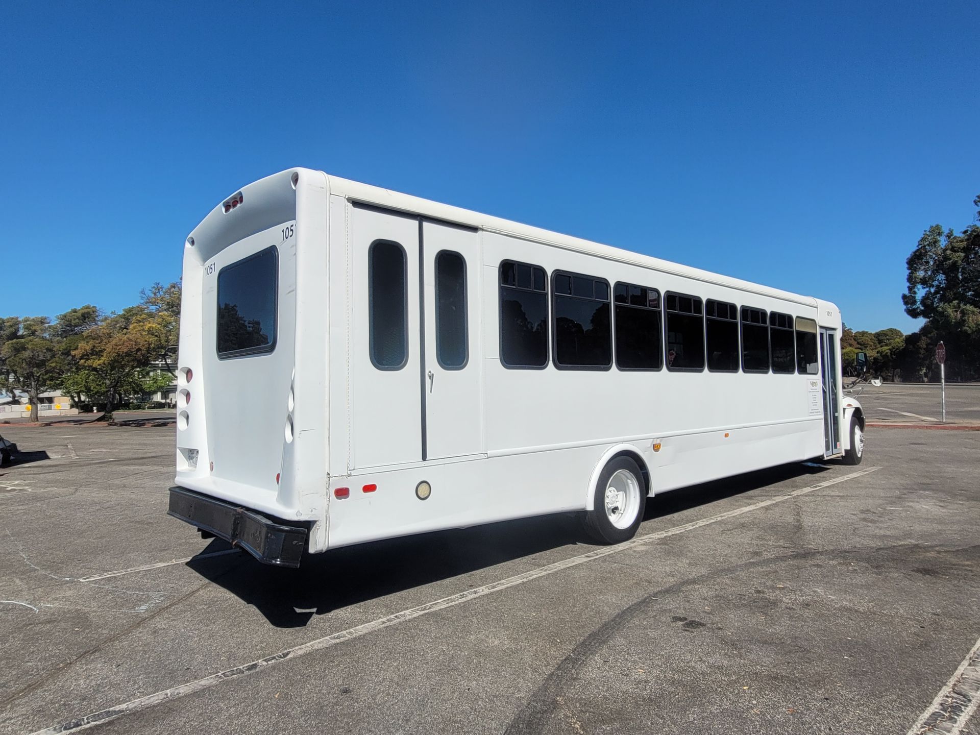 A white bus is parked in a parking lot.