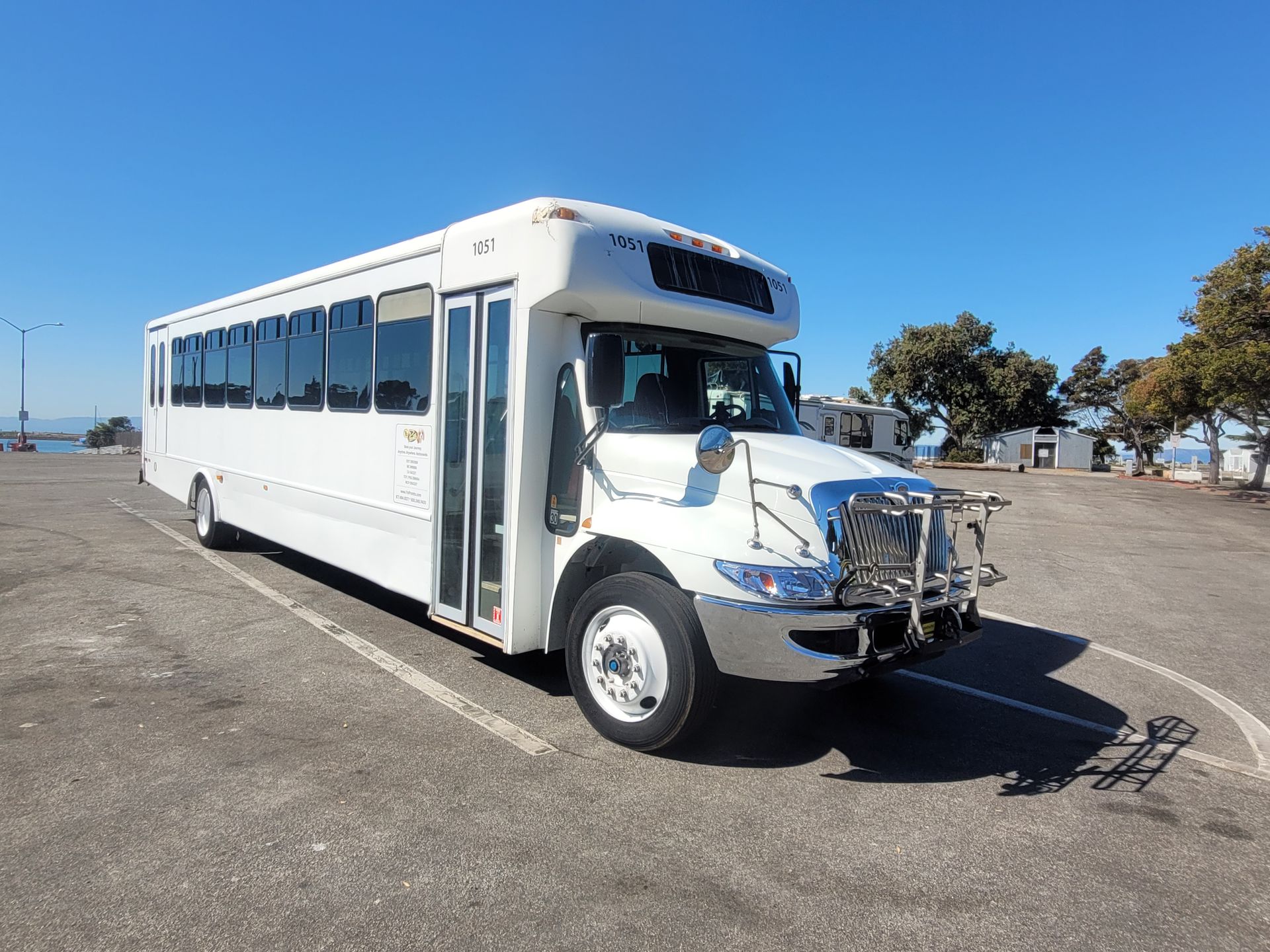 A white bus is parked in a parking lot.