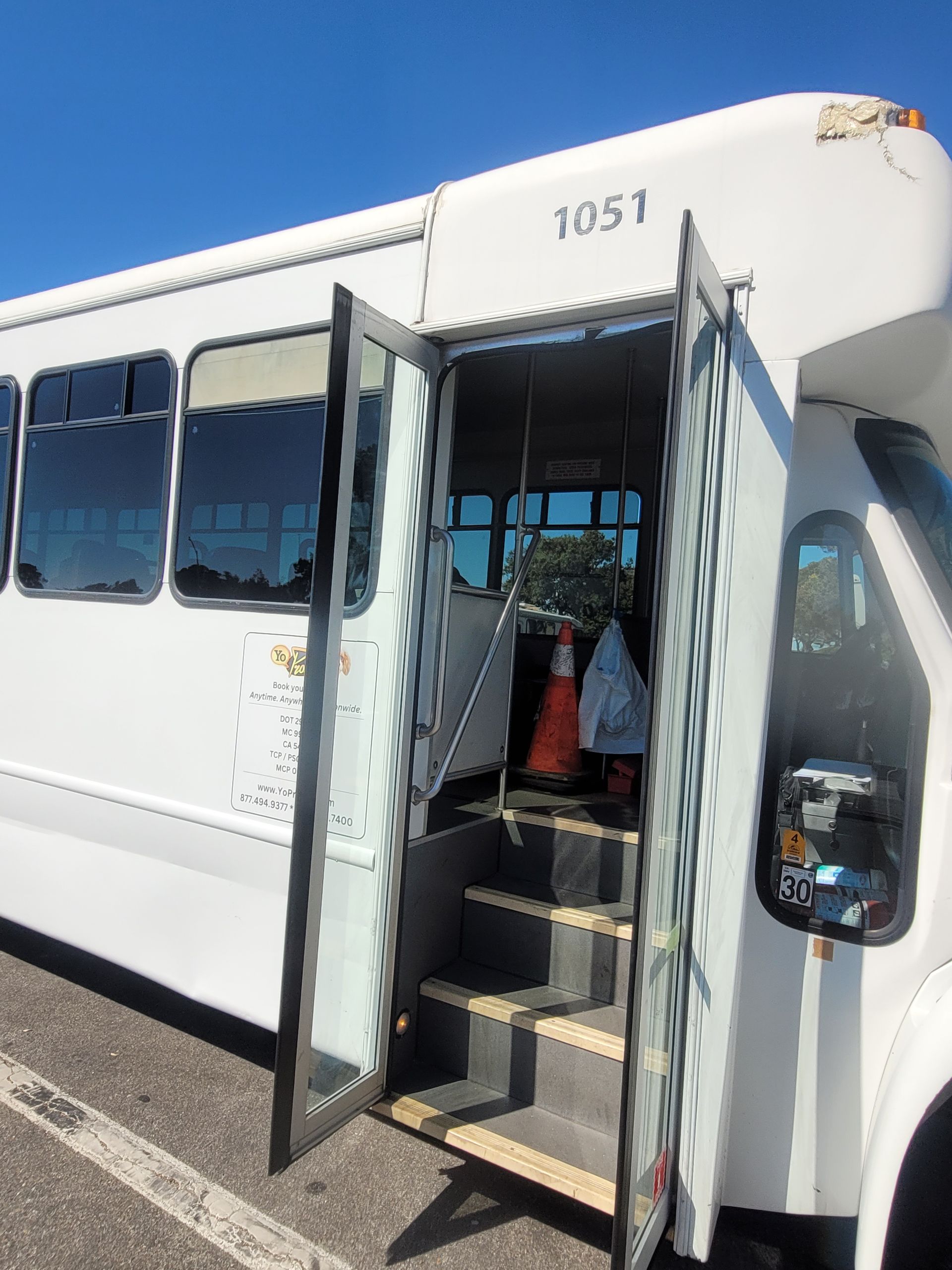 A white bus with the doors open is parked in a parking lot.