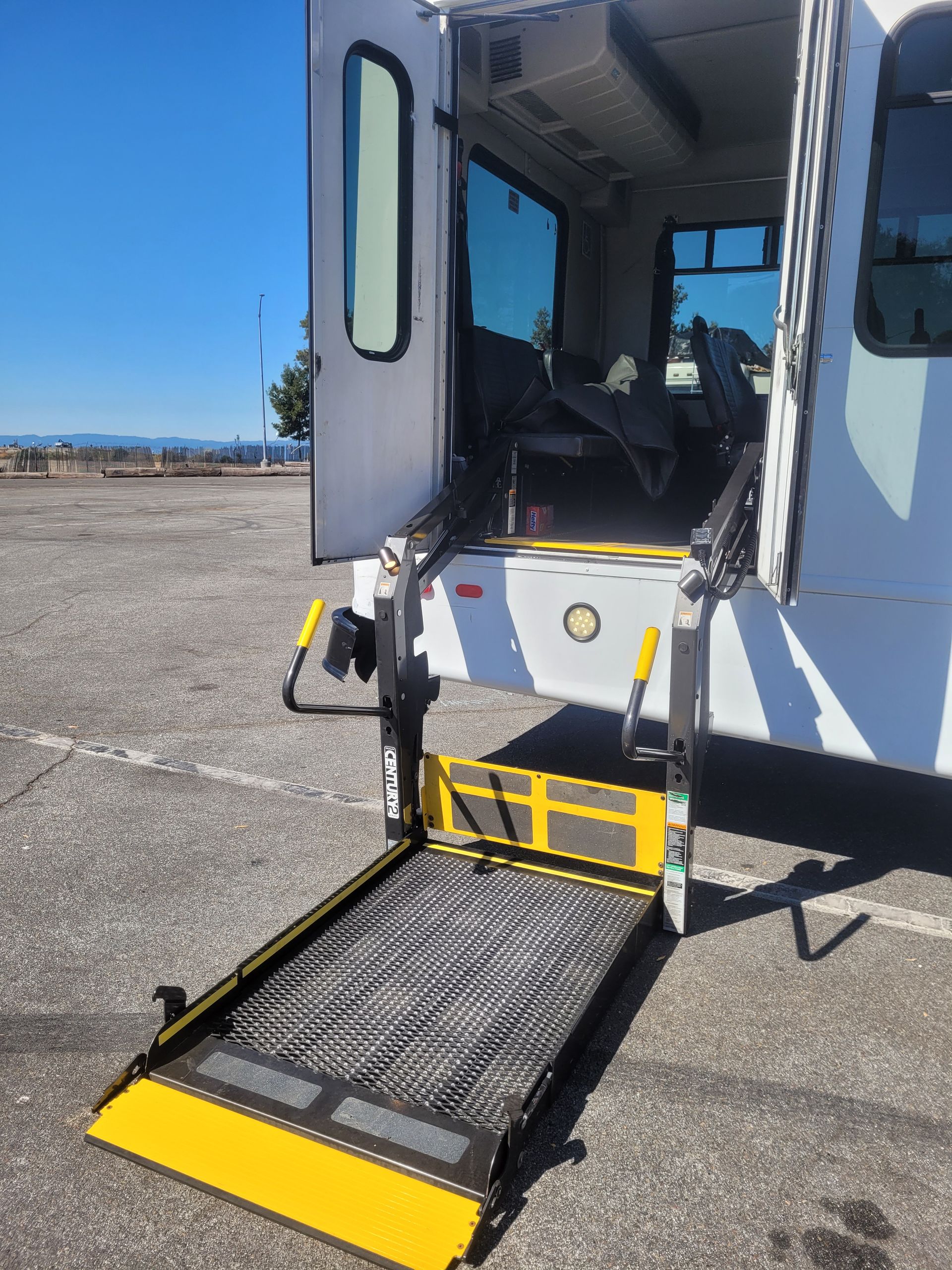A white van with a wheelchair lift is parked in a parking lot.
