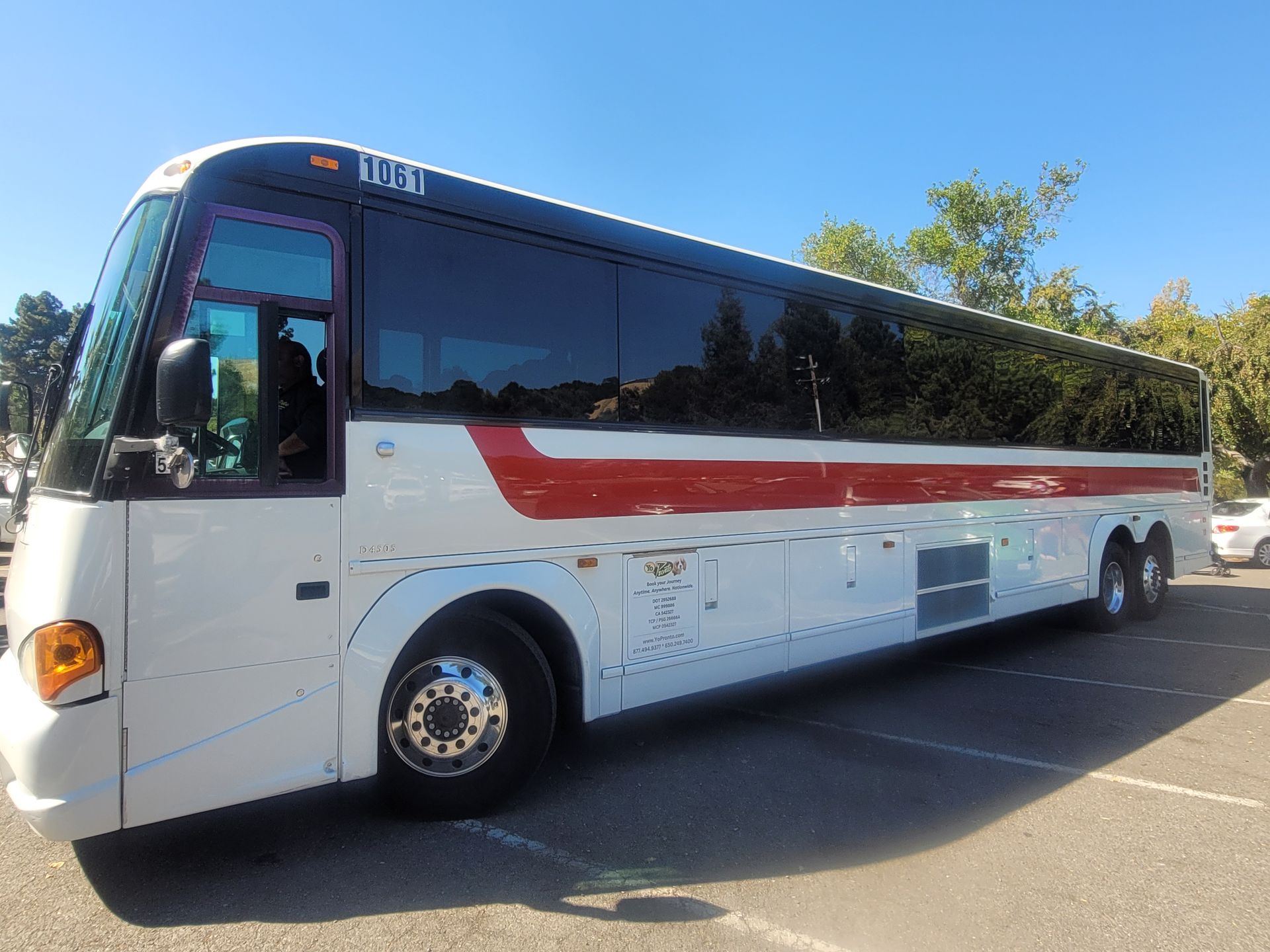 A white and red bus is parked in a parking lot