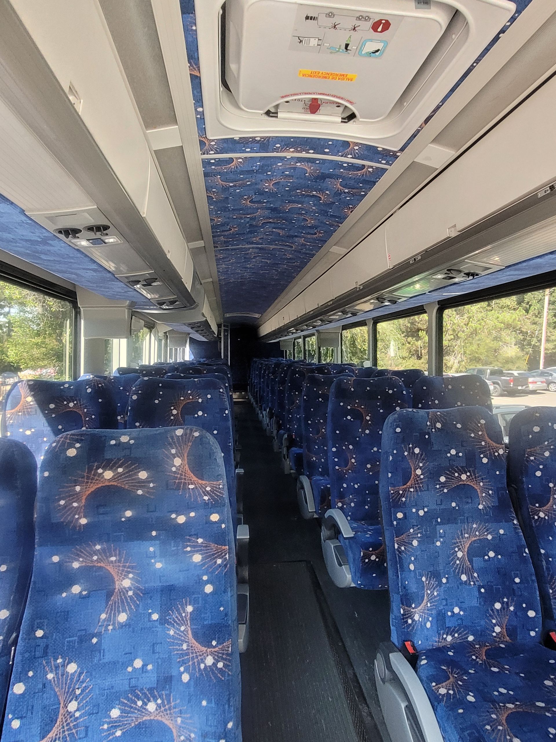 The inside of a bus with blue seats and a ceiling