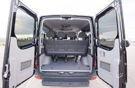 The back of a van with its doors open and a bench in the back.