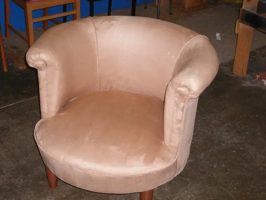 A tan chair is sitting on a concrete floor