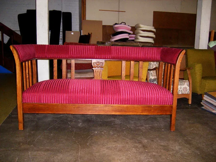 A wooden couch with a red striped cushion