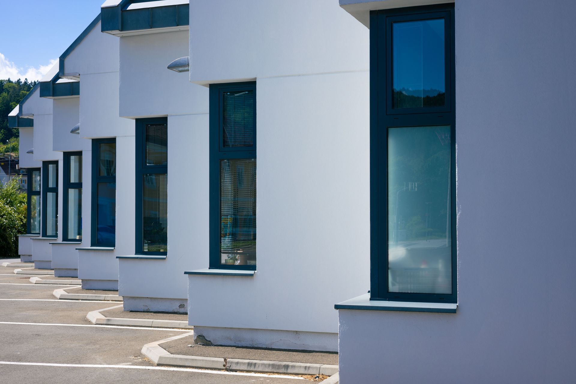 Row of white modern buildings with tall blue windows along a paved walkway