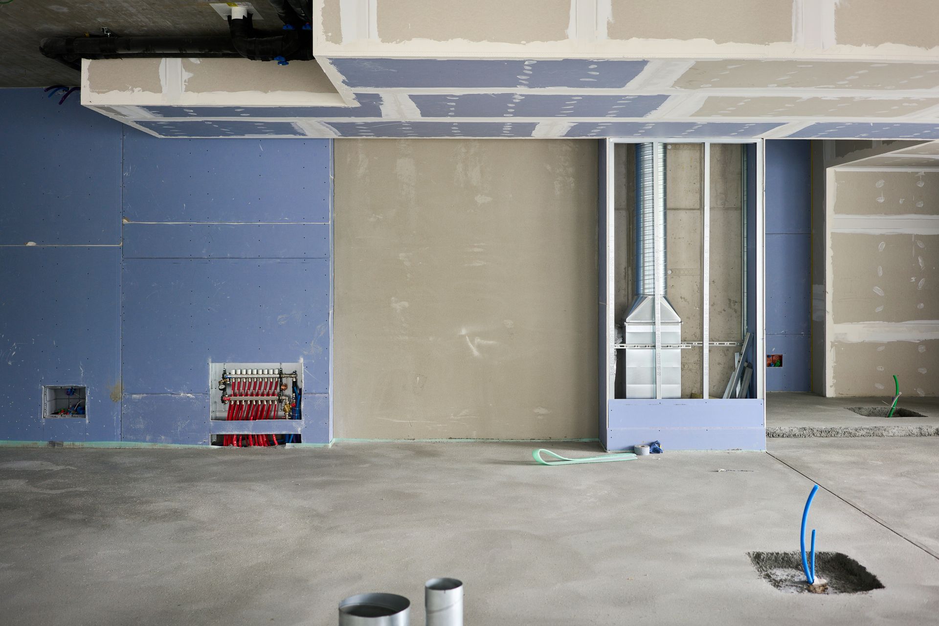Empty room under construction with exposed ceiling, unfinished walls, and electrical wiring on the floor