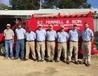 Group of members from E.T. Ferrel & Son pose in front of a red truck, under the summer rays