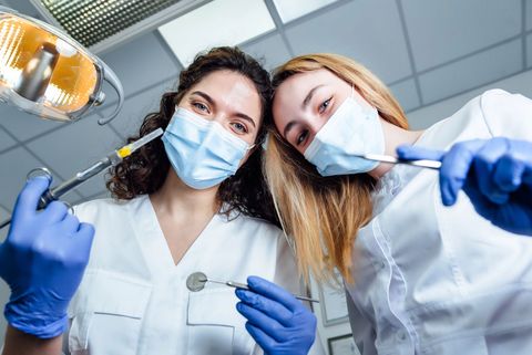 In una luminosa clinica dentistica, due dentisti con mascherine e guanti esaminano la telecamera.