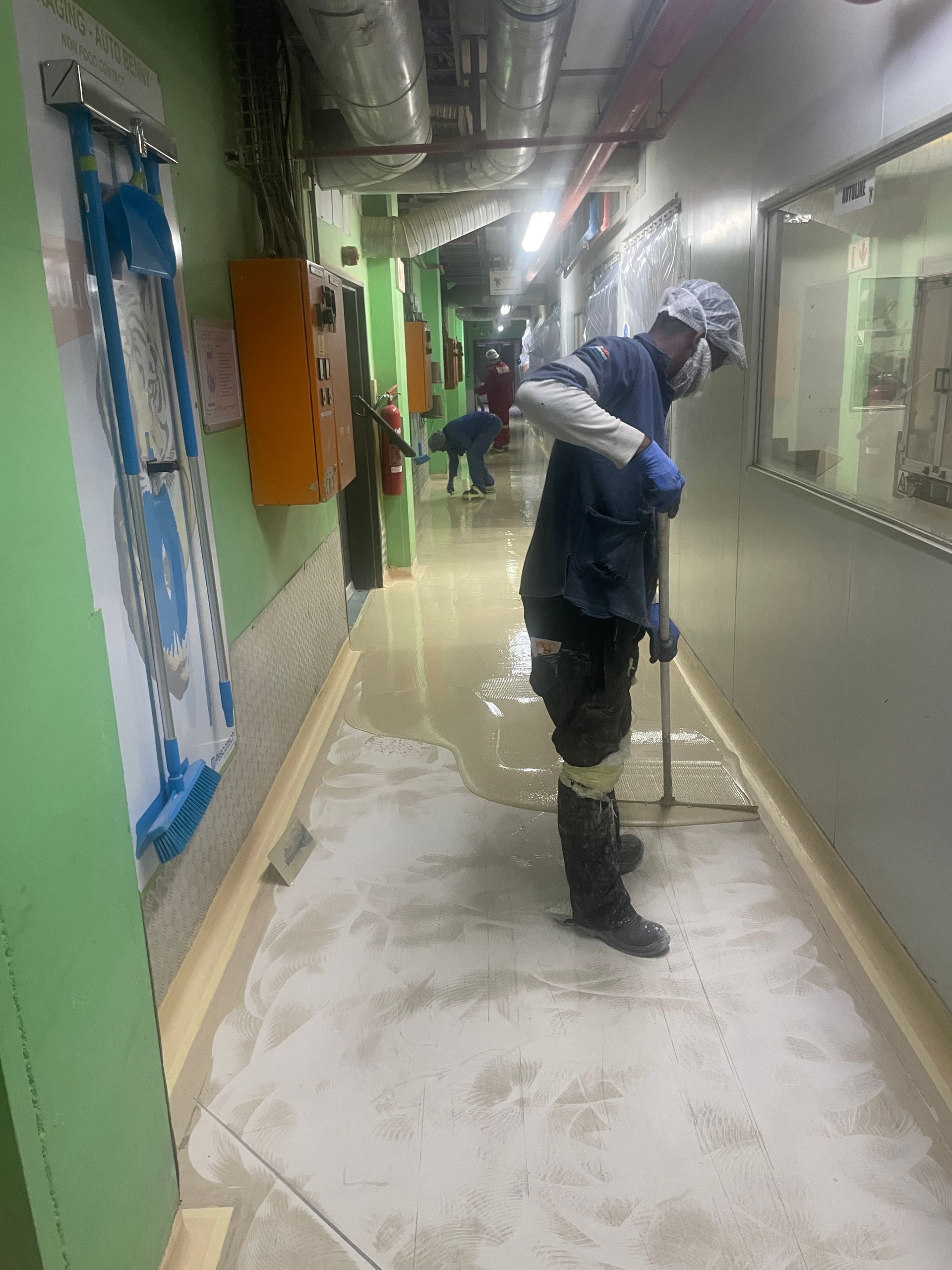 A man is cleaning a hallway with a mop.