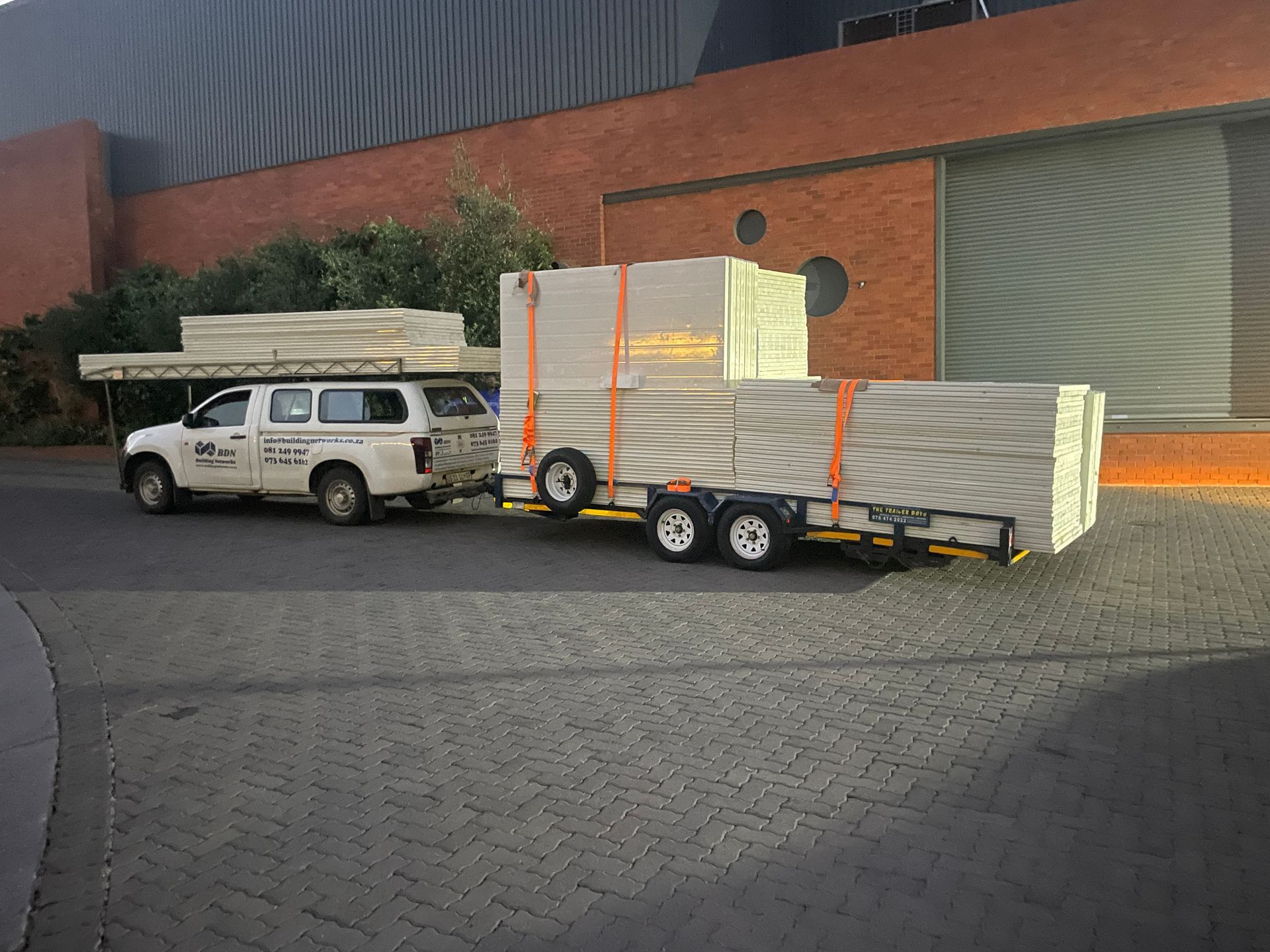 A white truck is pulling a trailer full of boxes