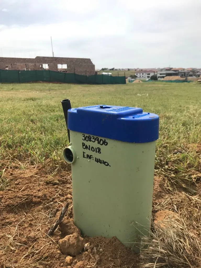 A white container with a blue lid is sitting in the middle of a field.