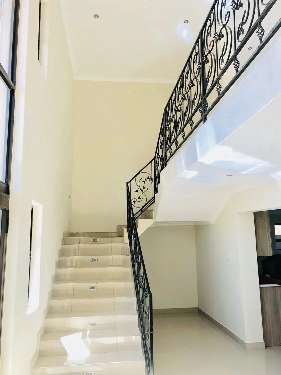 A staircase with a wrought iron railing leading up to the second floor of a house.