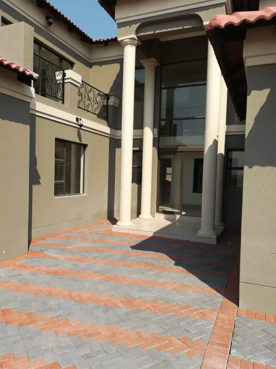A large building with columns and a brick driveway