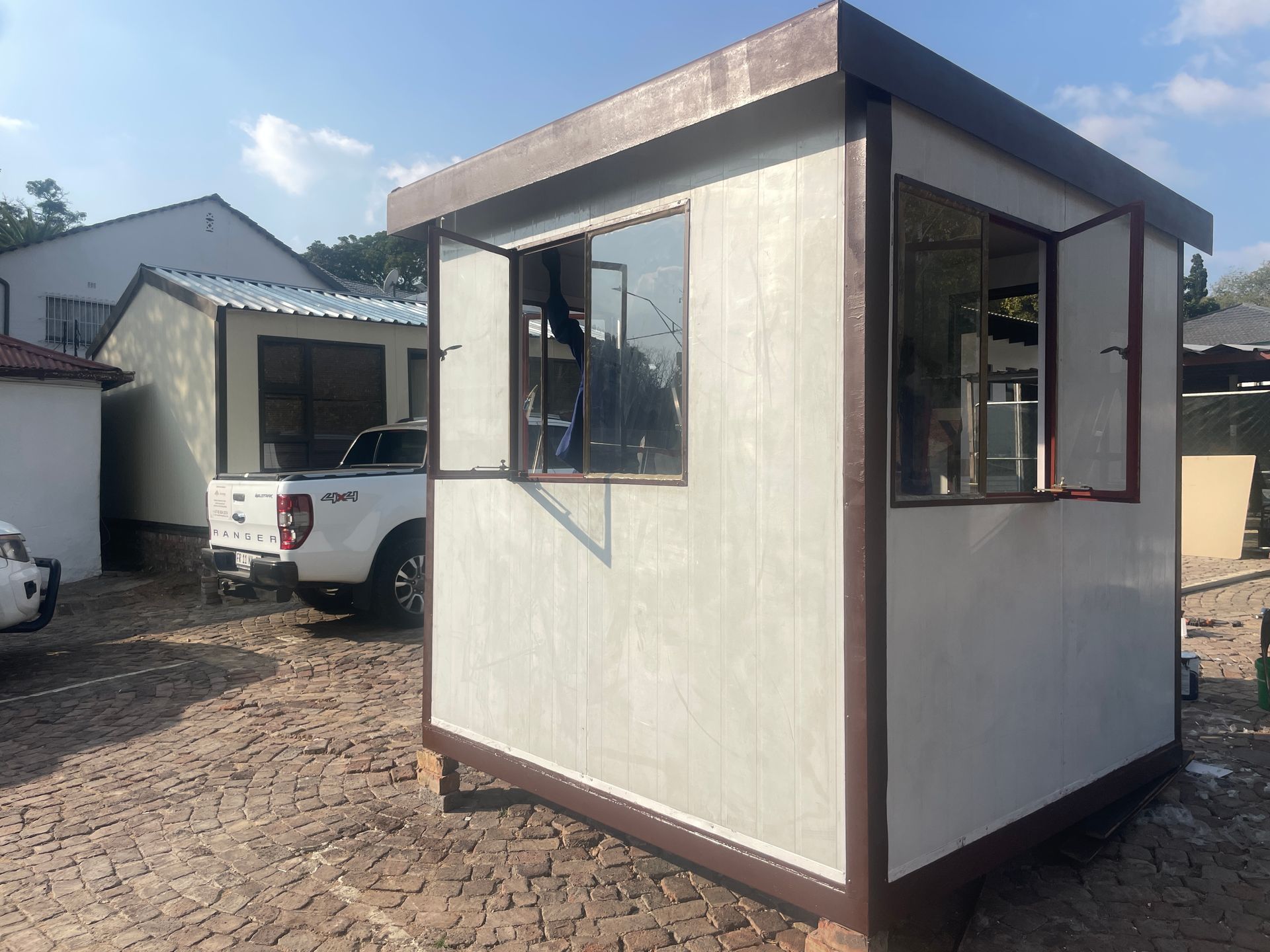 A white truck is parked in front of a small building.