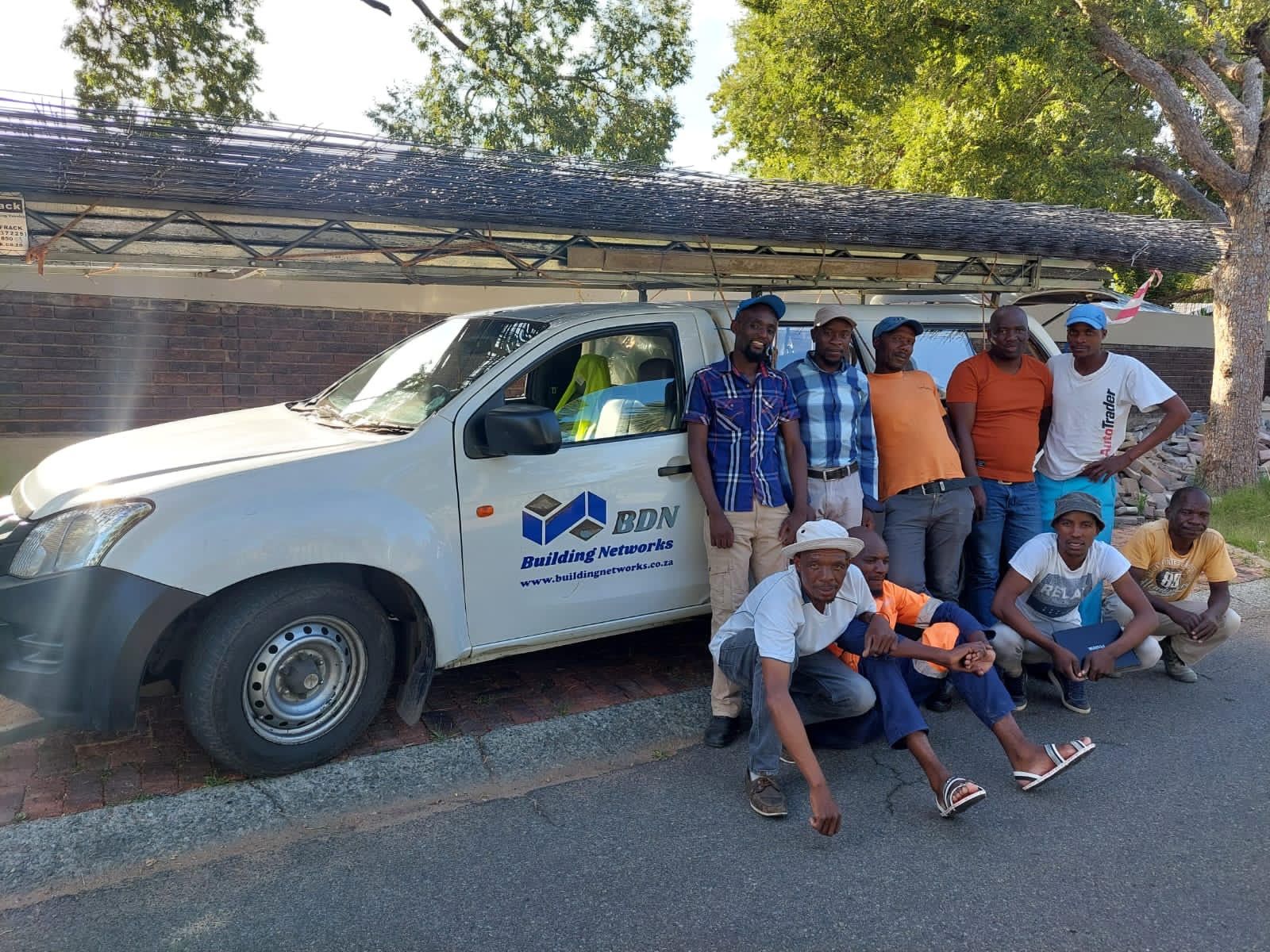 A group of men are posing for a picture in front of a truck.