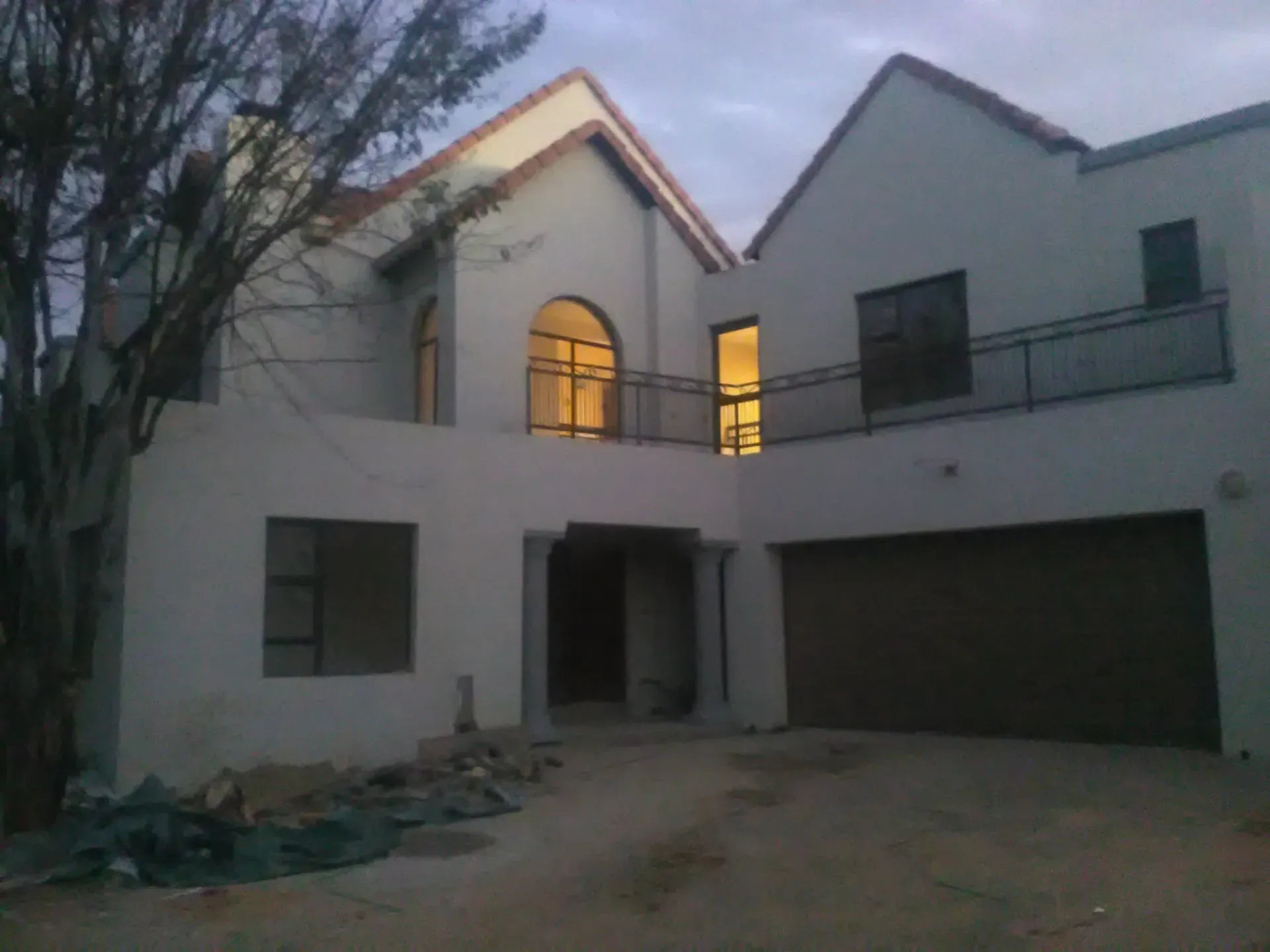 A white house with a brown garage door and a balcony