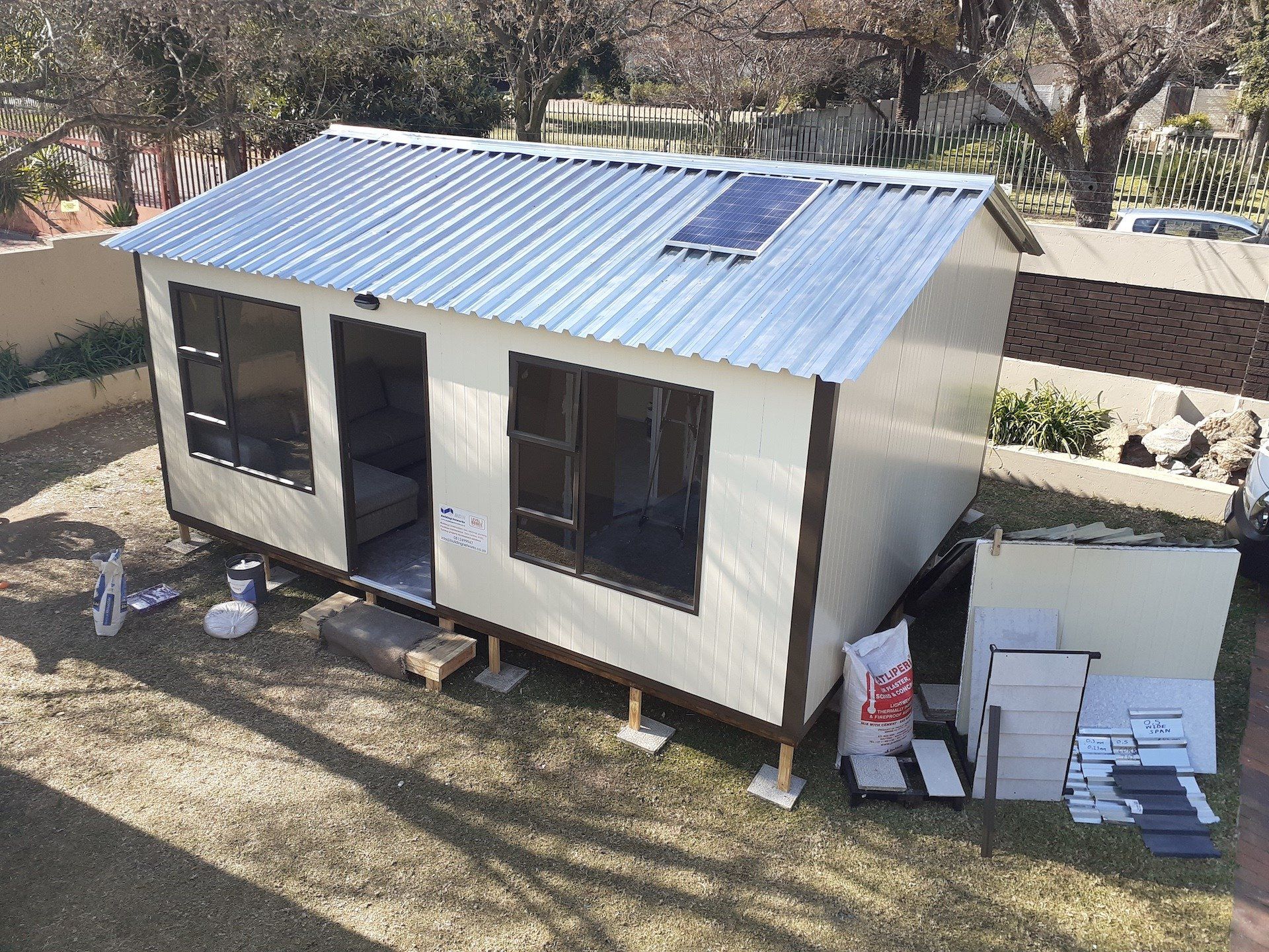A small house with a metal roof is being built in a backyard.