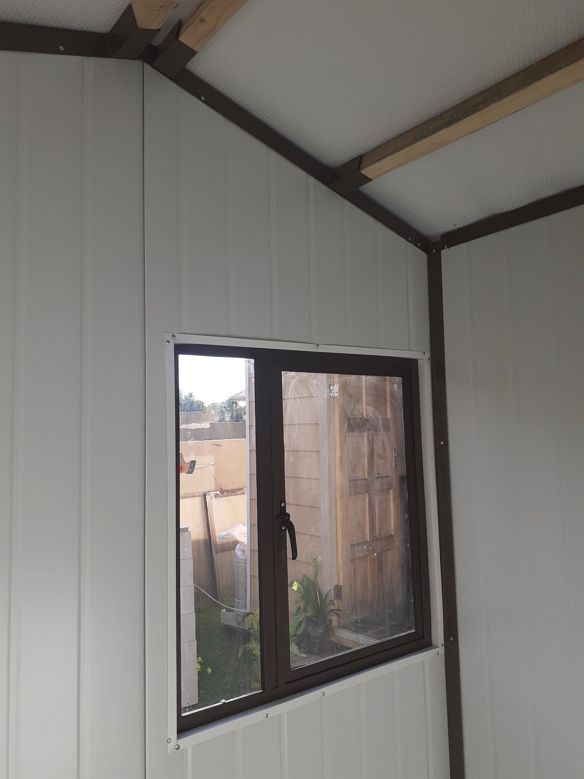A room with a window and a wooden ceiling.