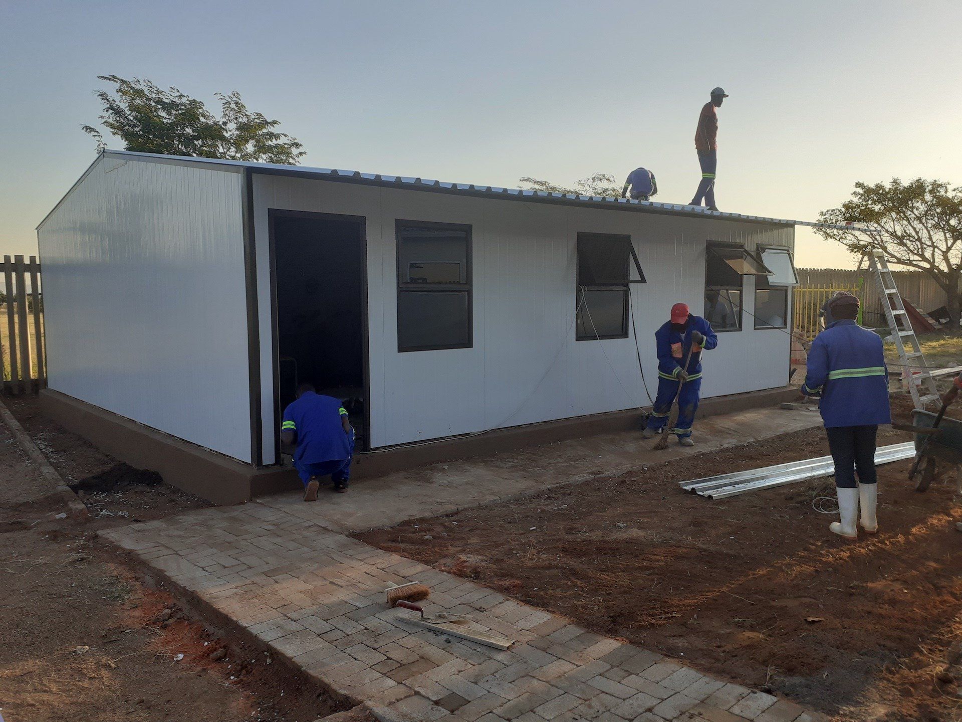 A man is standing on the roof of a white house.