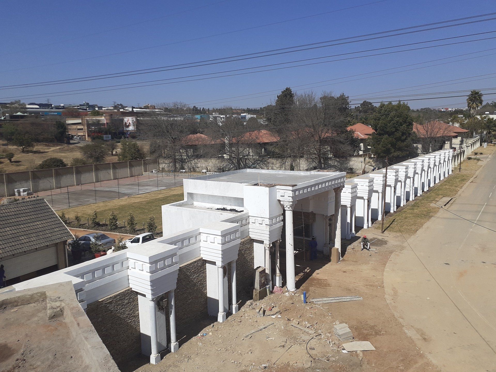 A large white building is being built next to a road.