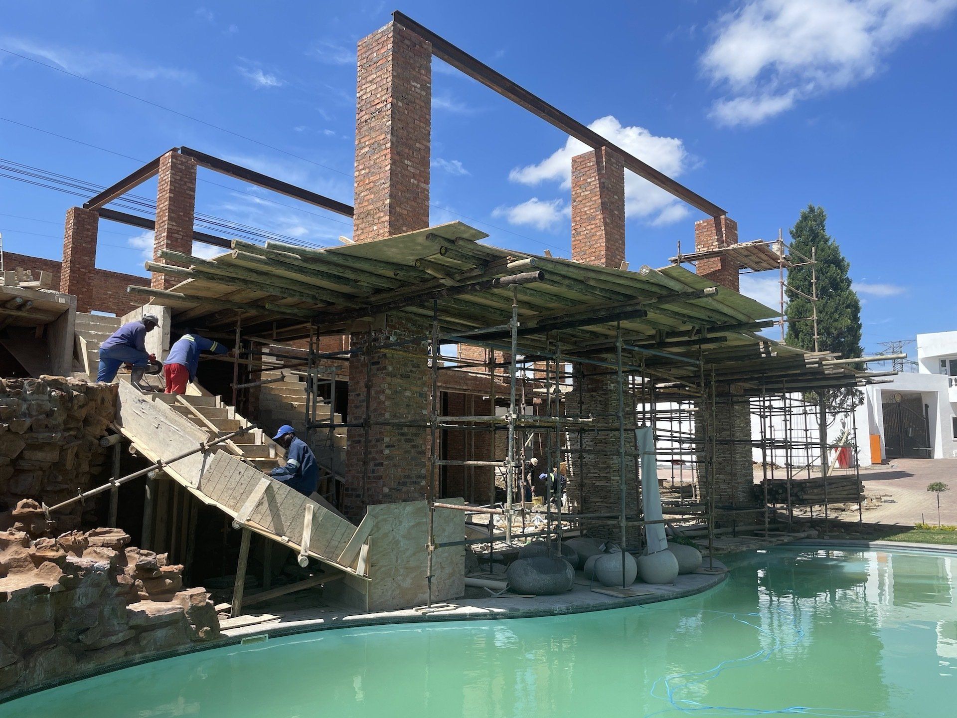 A building is being built next to a swimming pool.