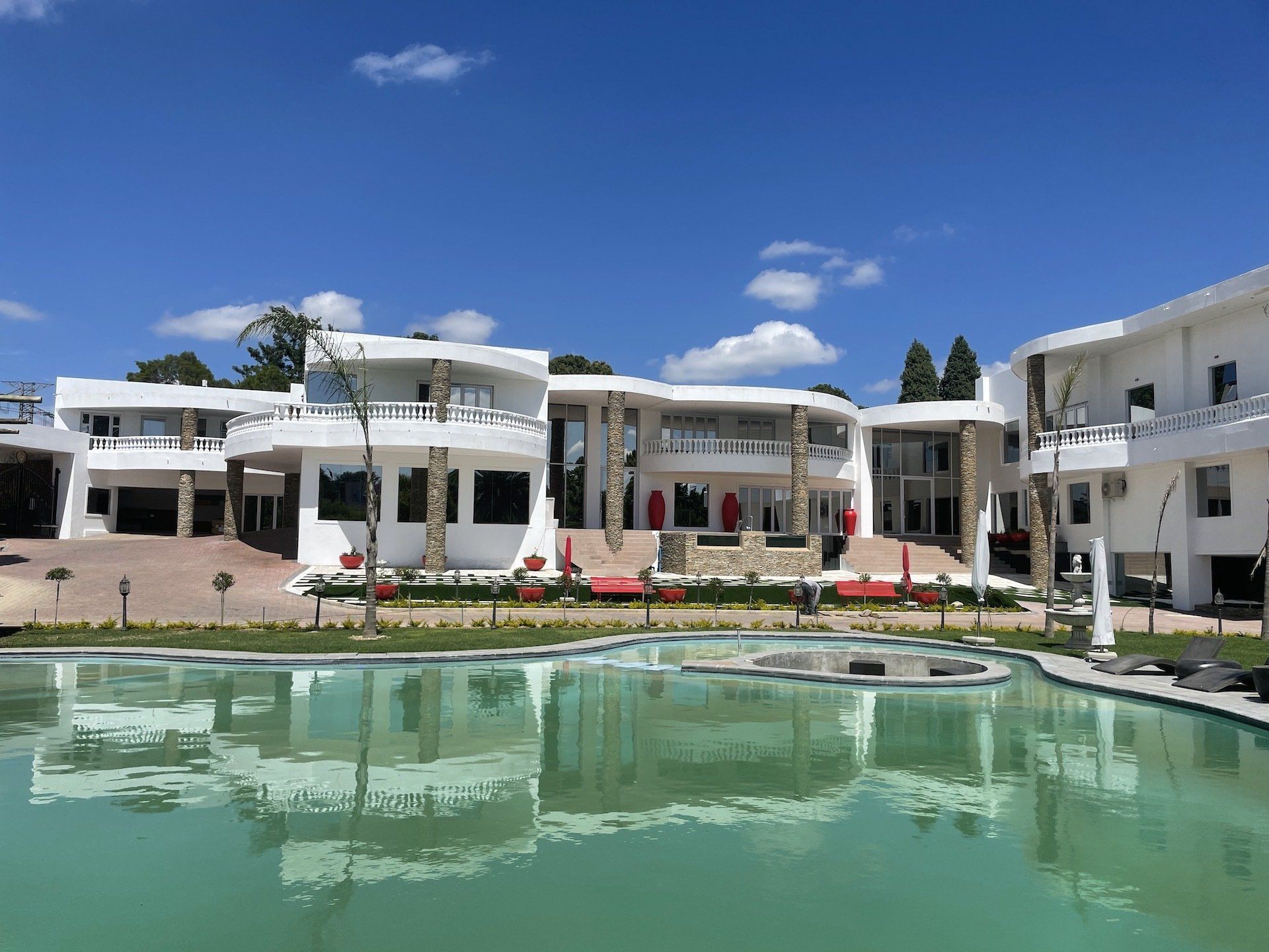 A large white building with a large swimming pool in front of it.