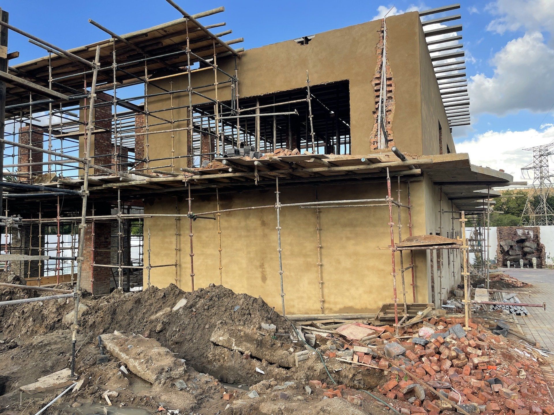 A building under construction with scaffolding around it and a pile of dirt in front of it.