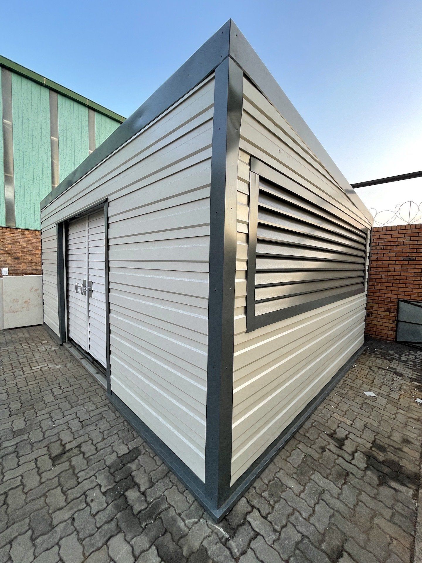 A white building with shutters on the windows is sitting on a brick sidewalk.